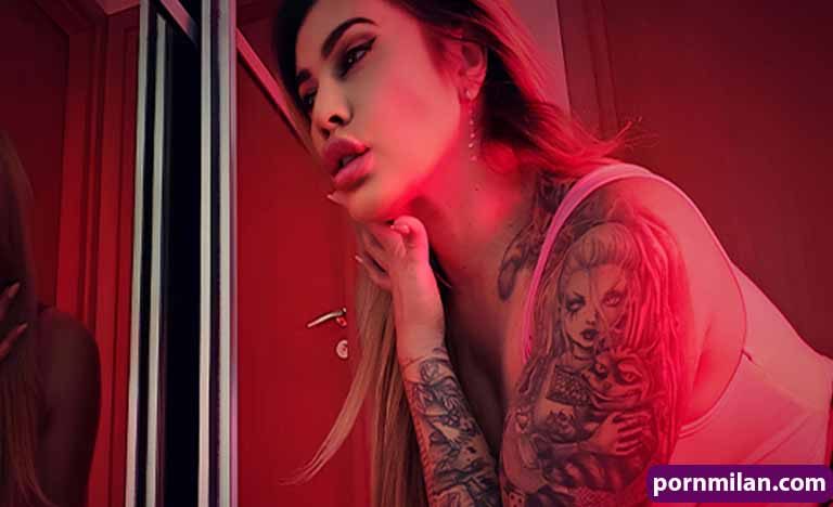 Gay Porn FM: The Smart Way To Travel The City Today Tattooed woman posing seductively in red lighting, leaning by a doorway.