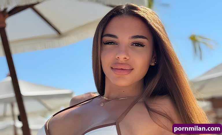 Senior casual dating: How to find real joy and fun every day Young woman with long brown hair posing outdoors in a white swimsuit top under a sunny sky and beach umbrellas in the background.